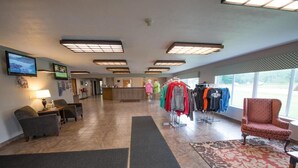 Un vestíbulo de hotel con una recepción, zona de estar y percheros.