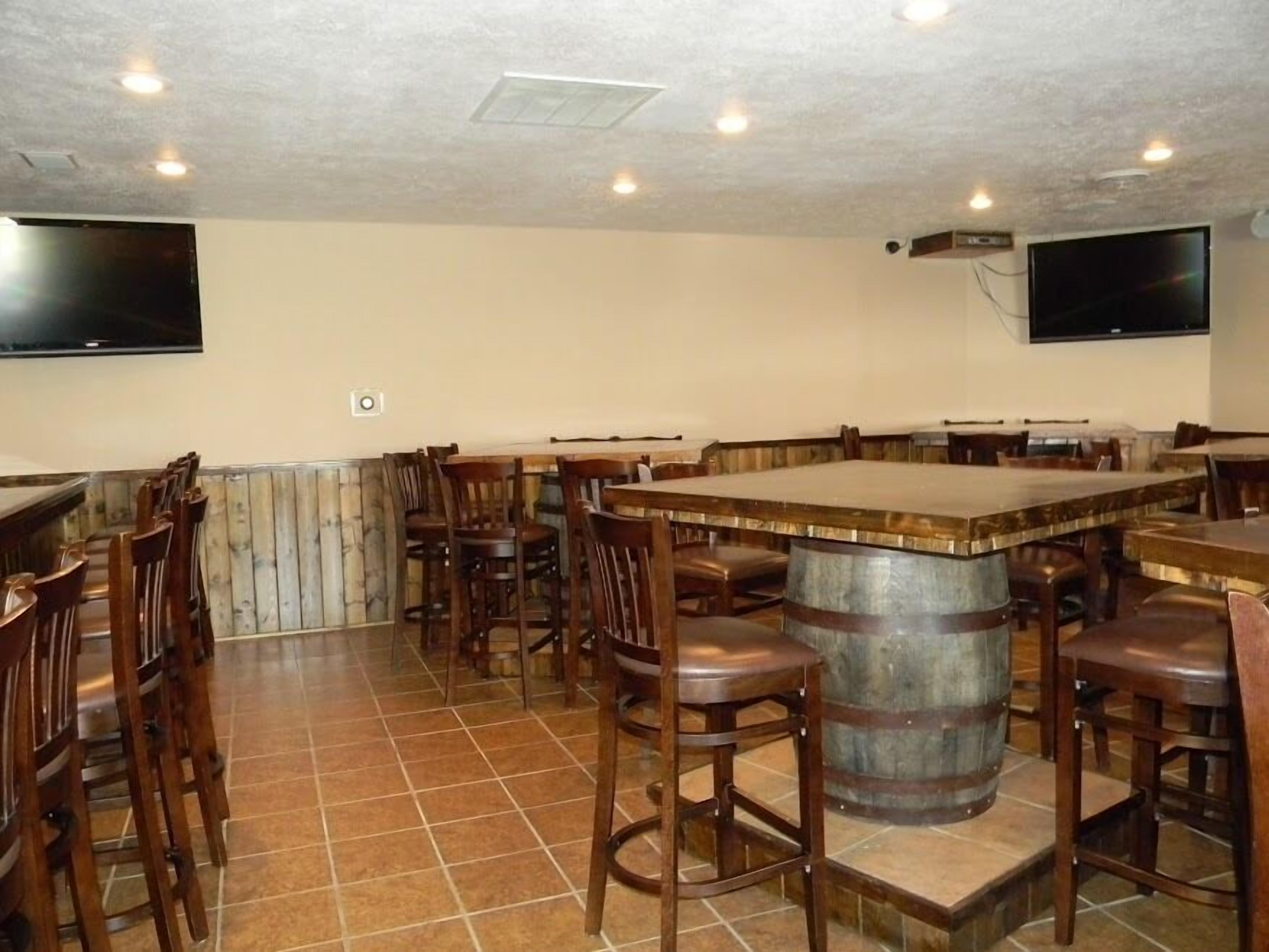 A bar area with wooden bar stools, a central bar counter, and a large barrel.