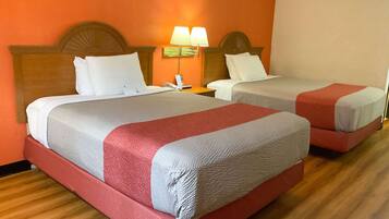 A hotel room with two beds, each with a headboard, a nightstand, a lamp, and a telephone.