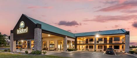 A hotel with a prominent sign, a covered parking area, and a well-lit entrance.