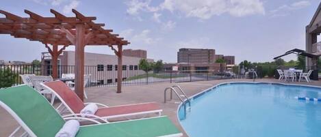 A pool area with lounge chairs and a pergola.