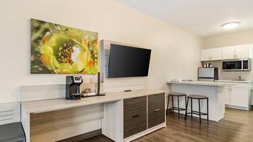 A modern kitchen with a flat-screen TV, a coffee machine, and a microwave.