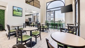 A spacious indoor dining area with multiple round tables and chairs, large windows, and a modern staircase. - The Bradford Hotel, an Ascend Collection Hotel (Springfield)