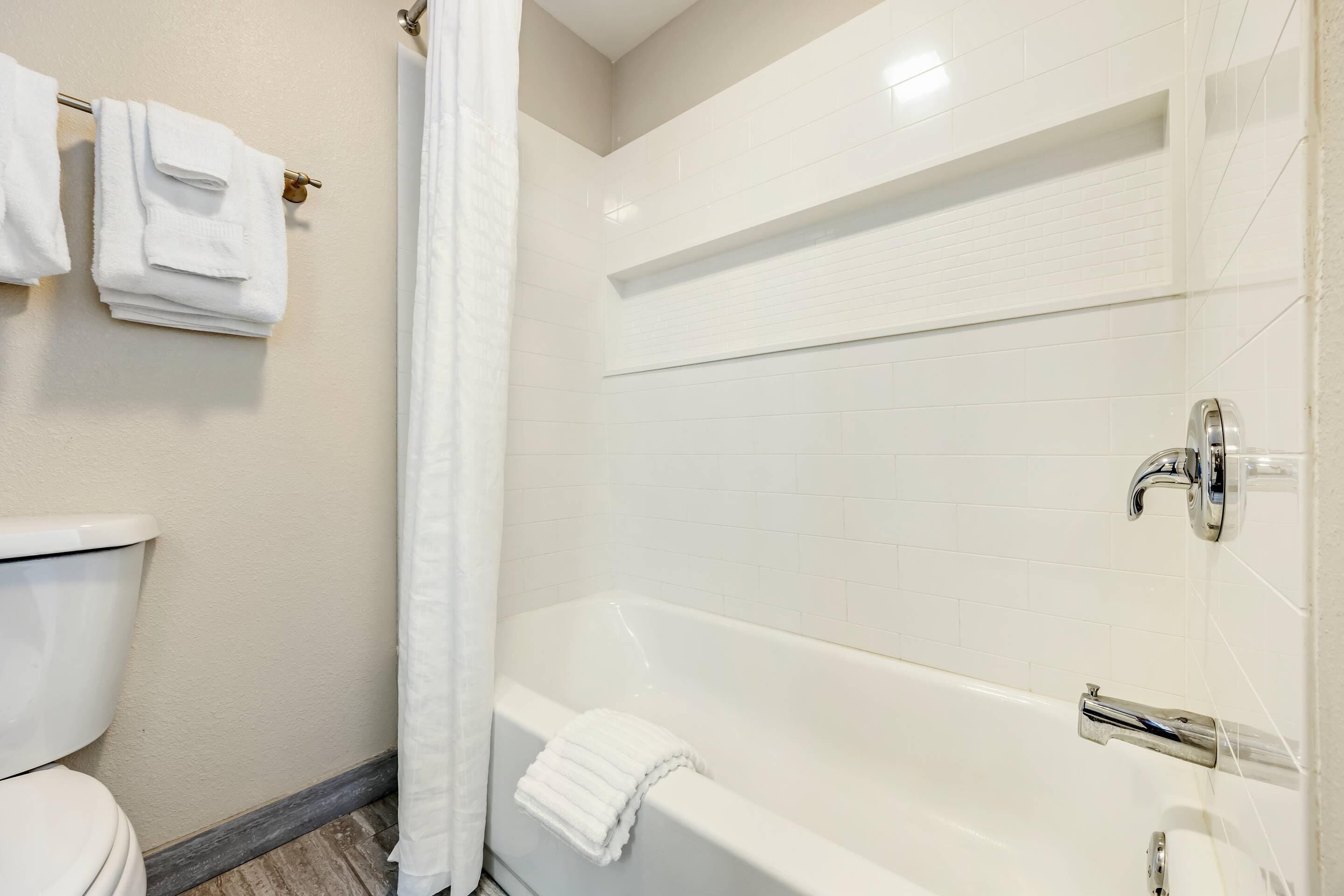 Une salle de bain avec une baignoire blanche, des toilettes et un porte-serviettes avec des serviettes pliées.