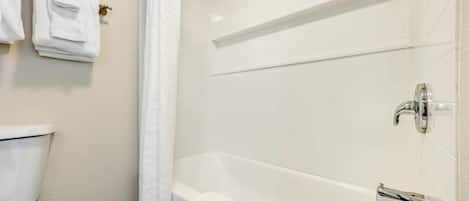 Une salle de bain avec une baignoire blanche, des toilettes et un porte-serviettes avec des serviettes pliées.