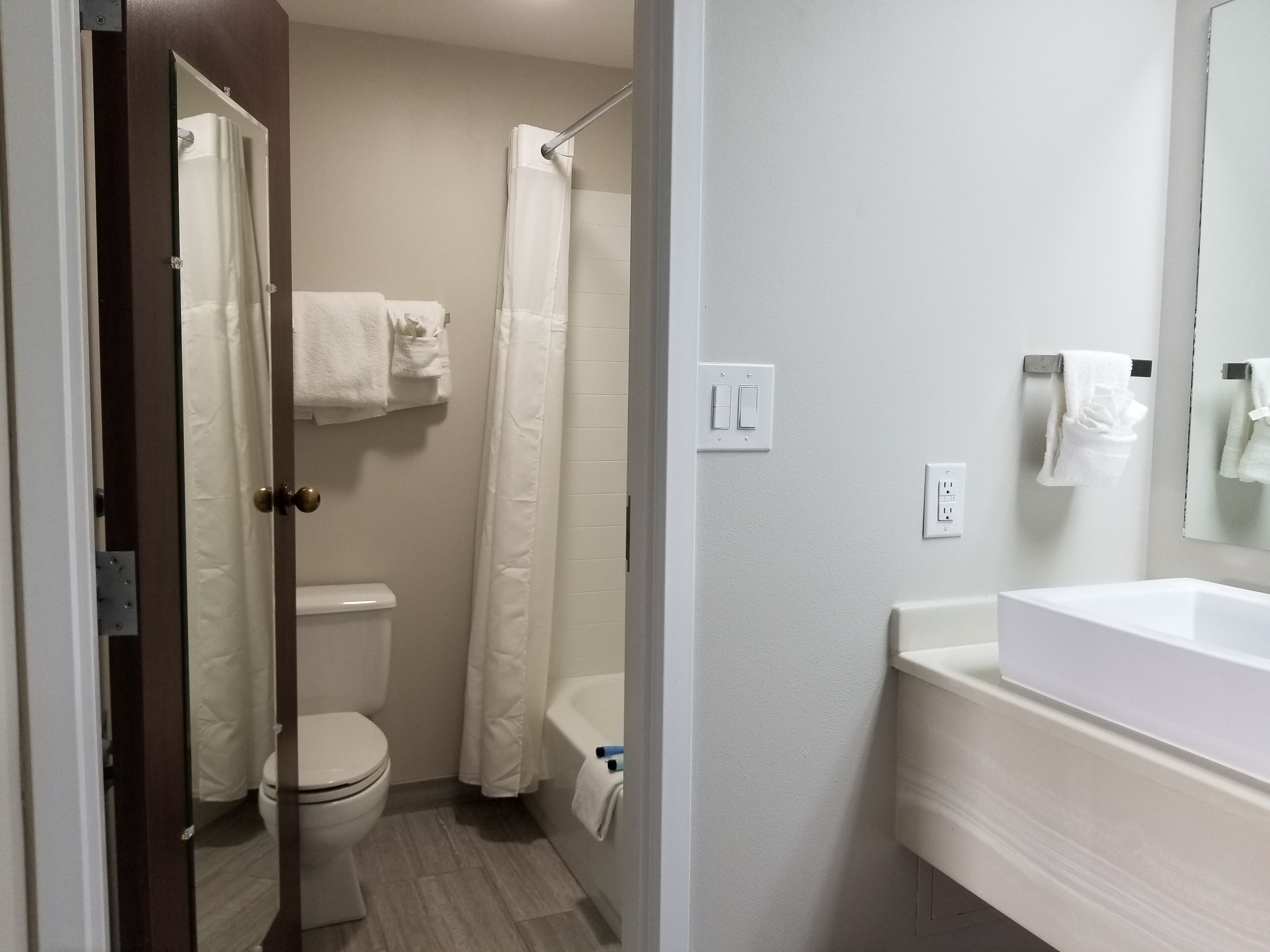 A bathroom with a toilet, shower, and sink.