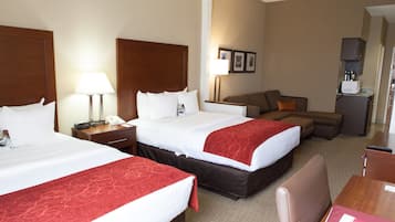 A hotel room with two beds, a sofa, a desk, and a kitchenette.