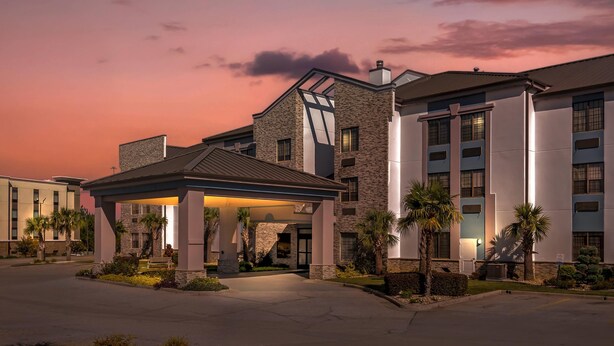 A hotel with a covered entrance, stone facade, and palm trees. - Comfort Suites Hattiesburg near University (Hattiesburg)