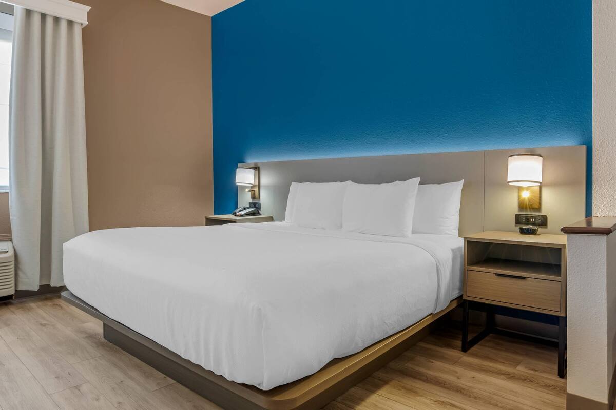 A hotel room with a large bed, bedside tables, and a nightstand.