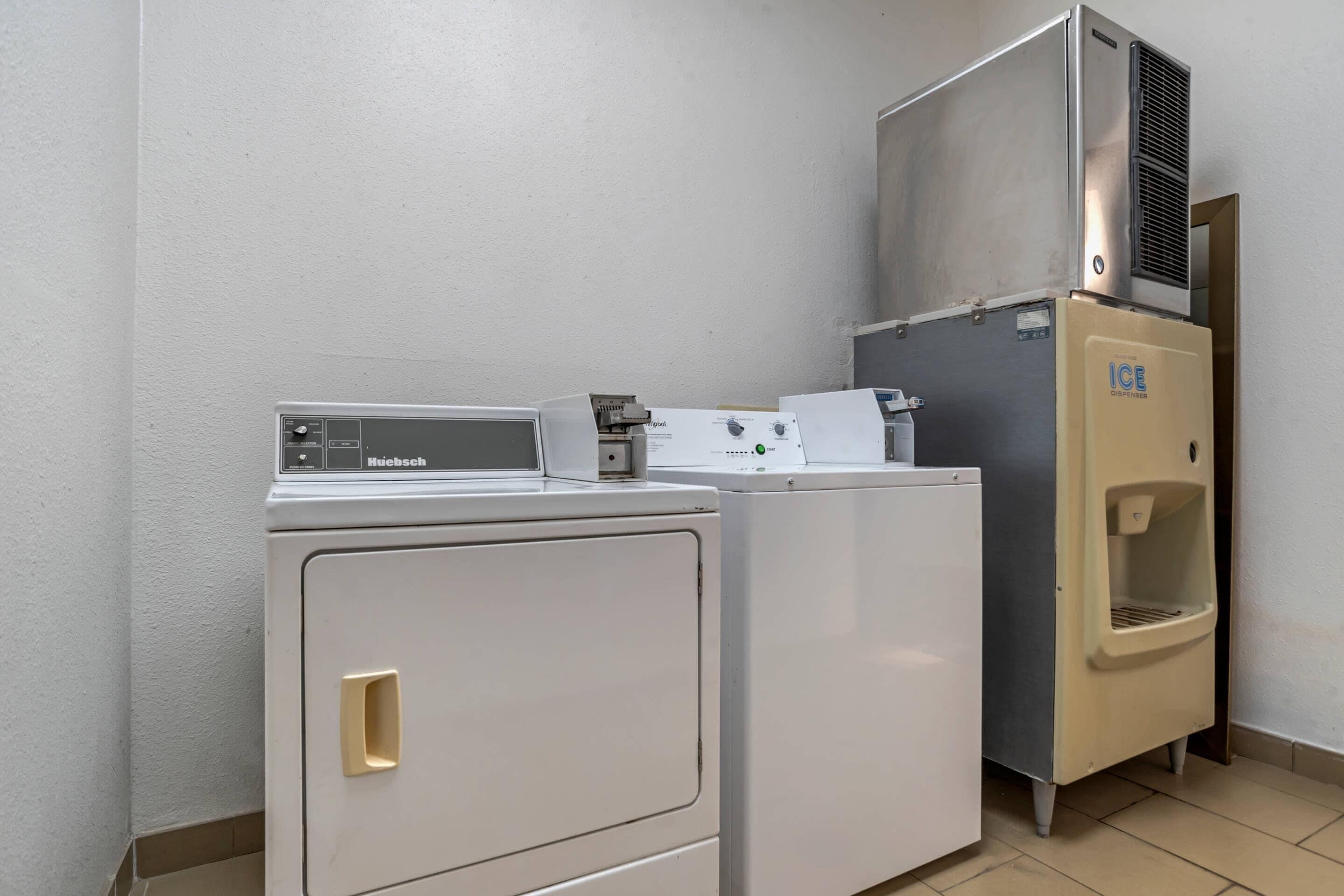 Un espace buanderie équipé d’un lave-linge à chargement frontal, d’un sèche-linge à chargement par le haut et d’un distributeur de glaçons.