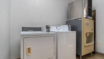 Un espace buanderie équipé d’un lave-linge à chargement frontal, d’un sèche-linge à chargement par le haut et d’un distributeur de glaçons.