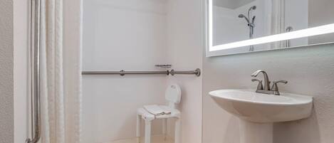Un bagno con doccia, WC, lavandino e specchio.