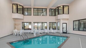 An indoor swimming pool with clear water, surrounded by white lounge chairs and a glass railing. - Comfort Suites Hattiesburg near University (Hattiesburg)