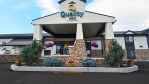 Un hôtel Quality Inn, appartenant au groupe Choice Hotels, avec une façade en pierre, une entrée couverte et un panneau indiquant « Stationnement interdit ».