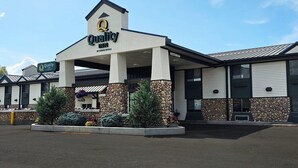 Un hôtel de la chaîne Quality Inn doté d’une façade en pierre, de grandes fenêtres et d’un espace d’entrée abrité.