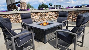 Une terrasse extérieure avec un mur en pierre, un foyer et quatre chaises.