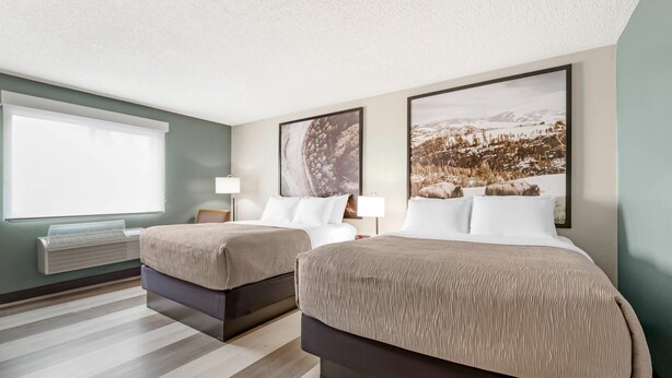 Une chambre d’hôtel avec deux lits, une grande fenêtre et un climatiseur fixé au mur.