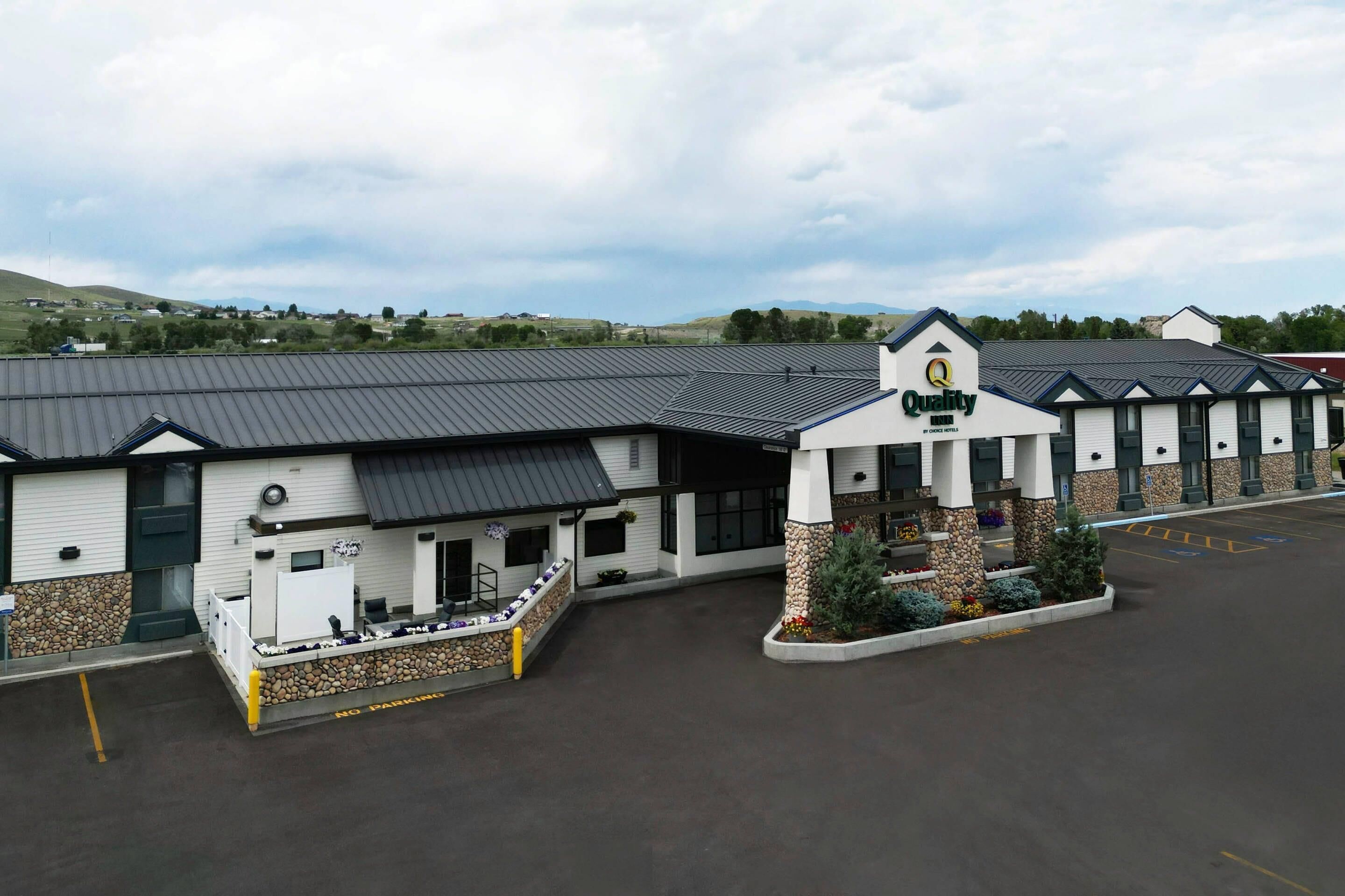 A hotel with a prominent entrance, a covered outdoor seating area, and a parking lot.