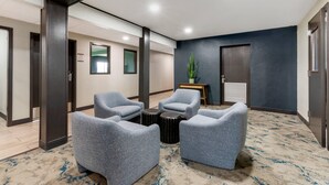 Un hall d’entrée moderne avec des fauteuils gris, une petite table et une plante en pot.