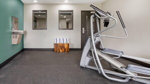 Une salle de remise en forme équipée d’un tapis de course, d’un distributeur d’eau et d’un miroir.