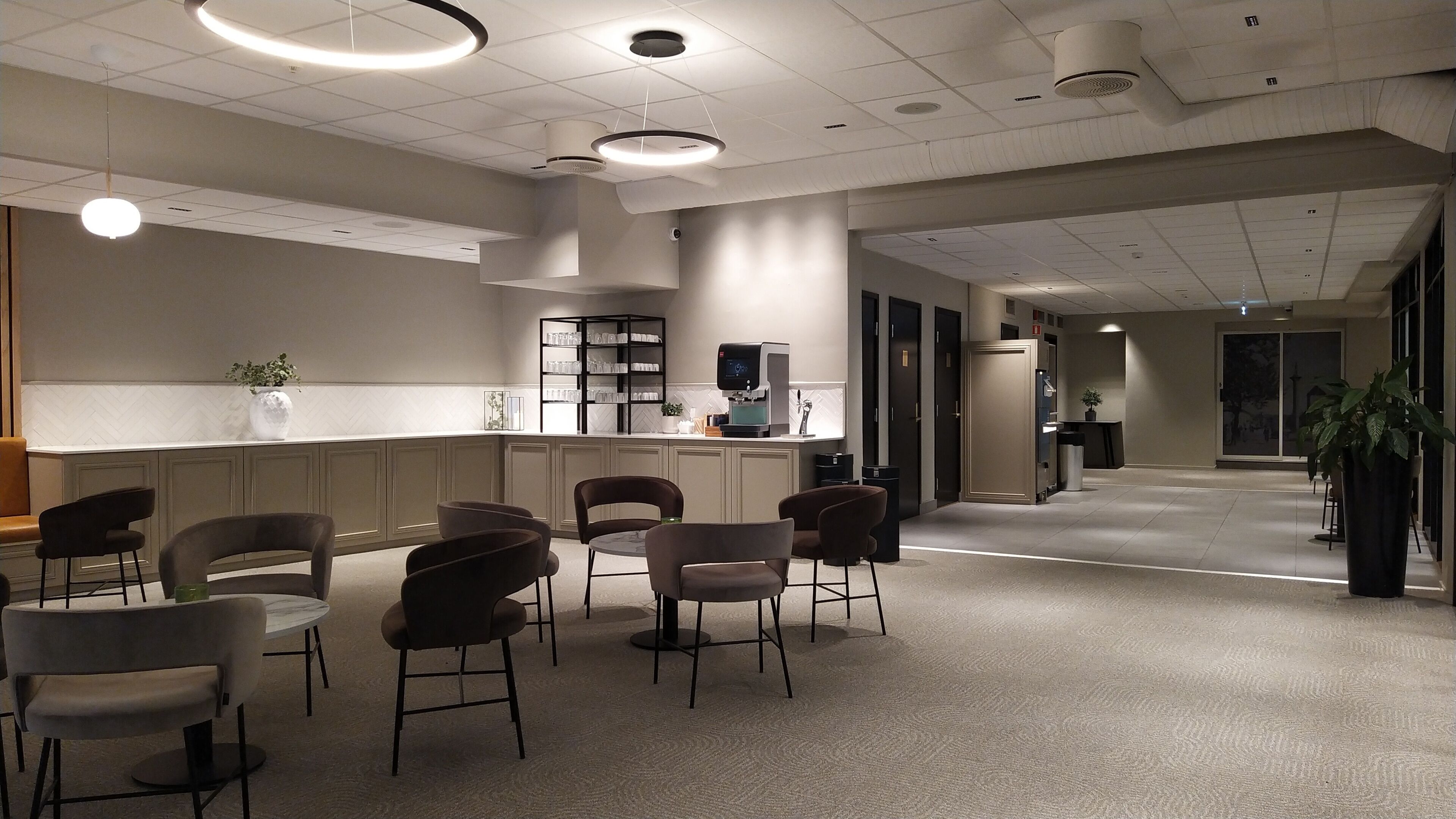 A modern interior with a reception desk, seating area, and a coffee machine.