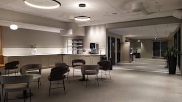A modern interior with a reception desk, seating area, and a coffee machine.