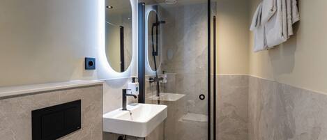 A modern bathroom with a glass-enclosed shower, a white sink, and a large mirror.
