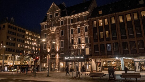 A hotel with a stone facade, large windows, and a Christmas tree outside. - Quality Hotel Augustin (Trondheim)