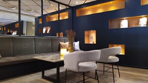 A modern interior with a dark blue wall, recessed lighting, a grey sofa, and a small table with a vase. - Quality Hotel Augustin (Trondheim)
