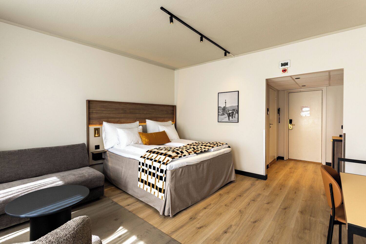A hotel room with a bed, a sofa, a dining table, and a chair.