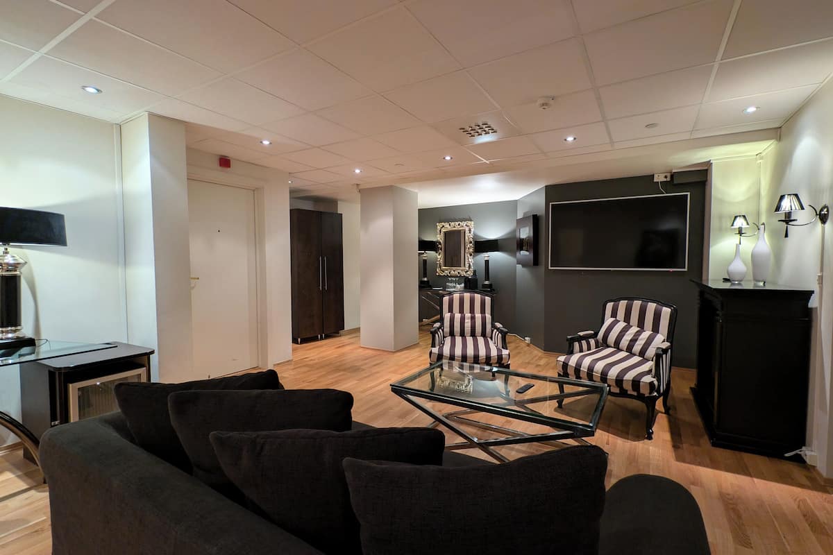 Uma sala de estar moderna com uma mesa de centro de vidro, poltronas listradas e uma TV de tela plana fixada na parede.