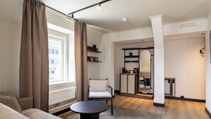 A modern living room with a sofa, armchair, round coffee table, and a mirror. - Quality Hotel Augustin (Trondheim)