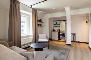 A modern living room with a sofa, armchair, round coffee table, and a mirror.