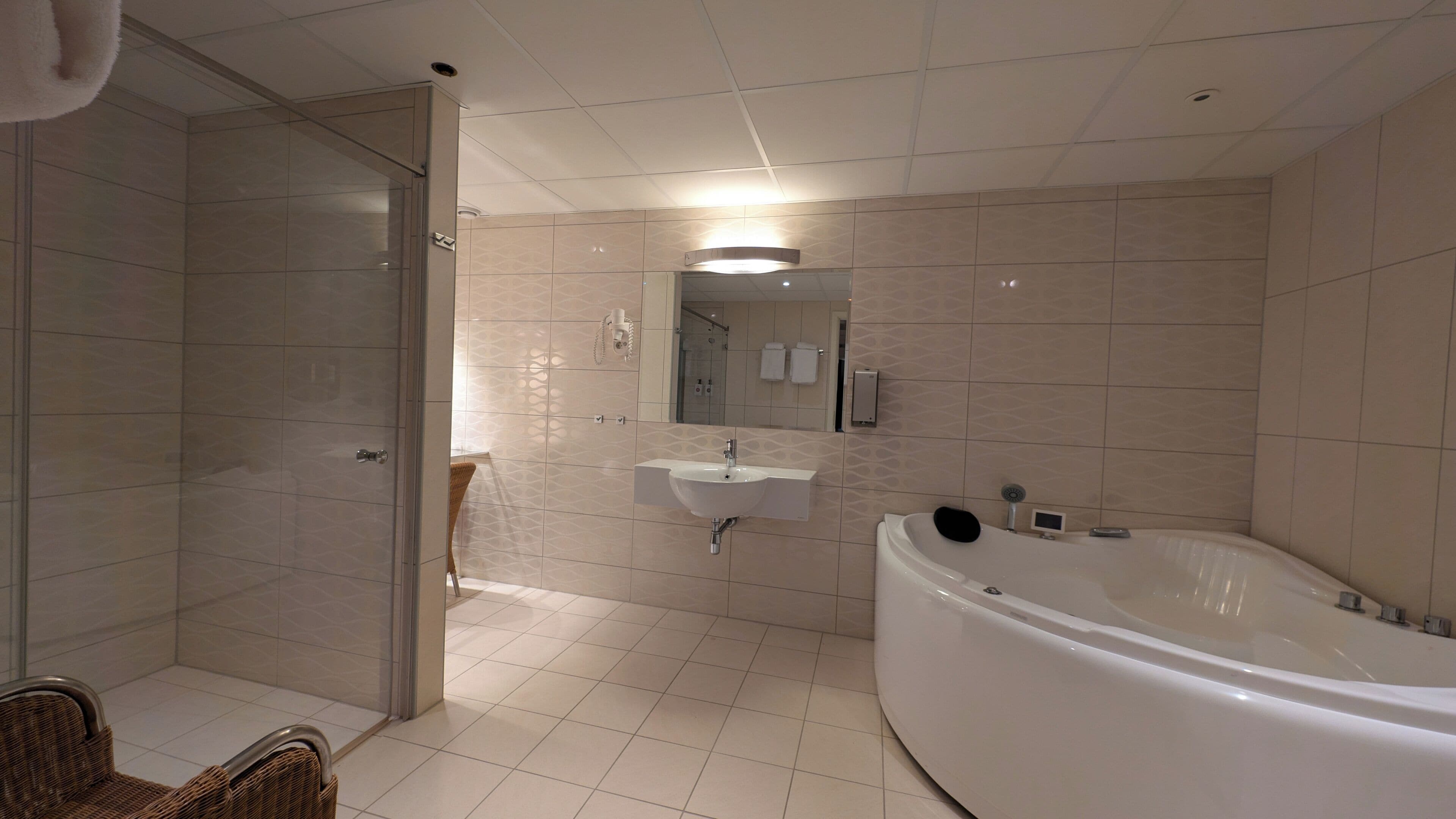 Ein modernes Badezimmer mit bodenebenen Dusche, freistehender Badewanne und einem wandmontierten Waschbecken.