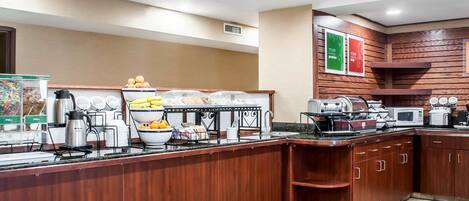 A buffet setup with various food items and appliances like a coffee maker, microwave, and toaster.