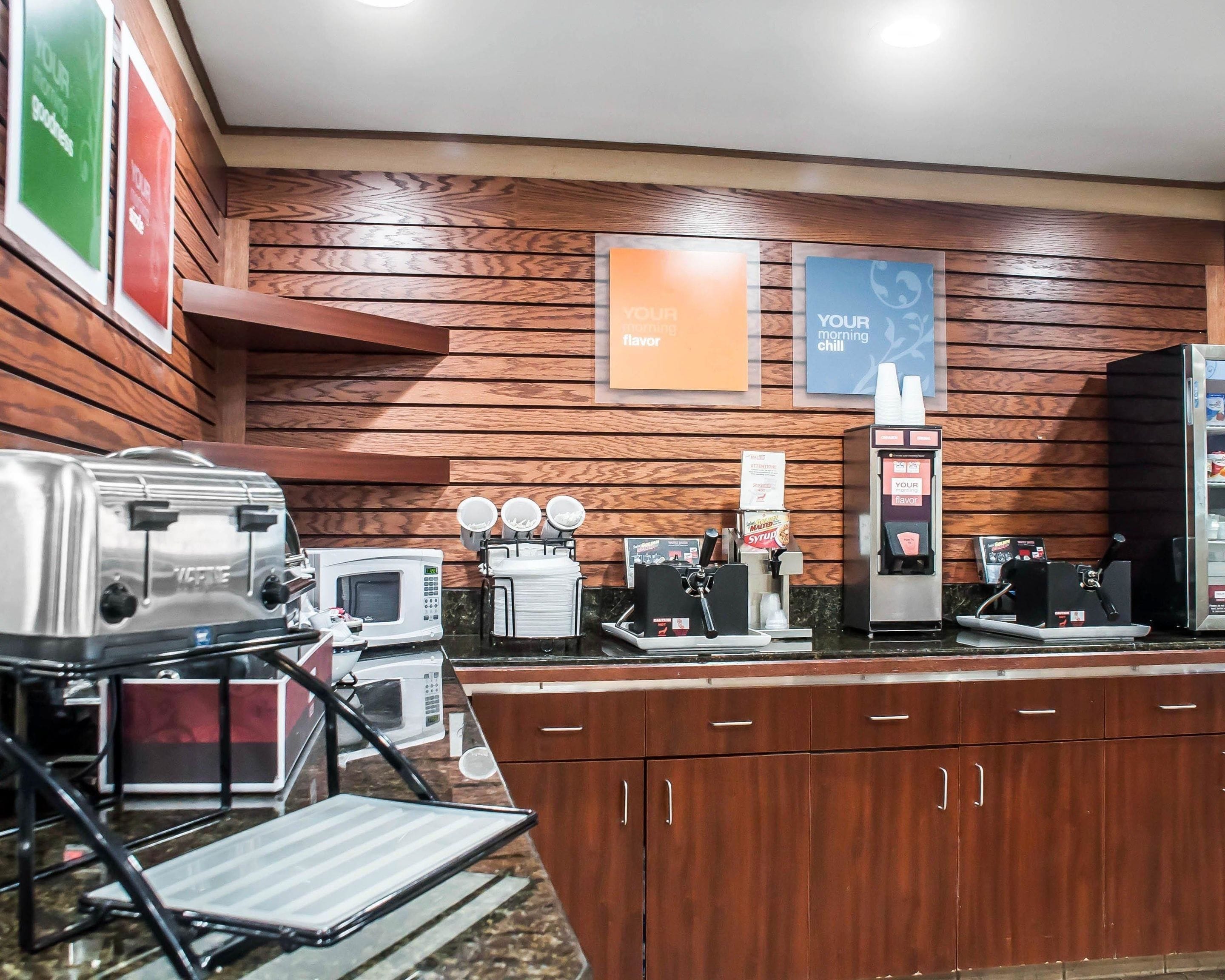 A kitchenette with a toaster, microwave, coffee maker, and a beverage dispenser.