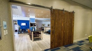 A modern hotel lobby with a wooden sliding door, a reception desk, and a seating area with a blue carpet. - Holiday Inn Express Canton by IHG (Canton)