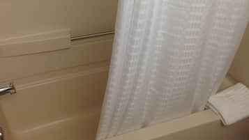 Una bañera con una cortina de ducha blanca y una toalla al lado.