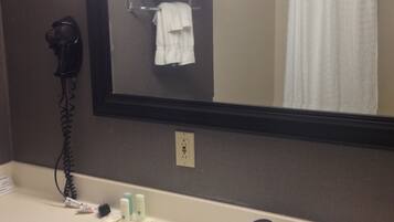 A bathroom with a sink, a hairdryer, and a mirror.
