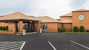 A building with a brick facade, a covered entrance, and a parking lot.