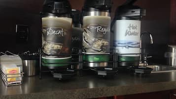 Una encimera de cocina con tres cafeteras etiquetadas 'Decaf', 'Regular' y 'Agua Caliente'.