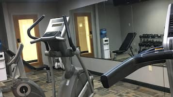 A gym with stationary bikes, treadmills, and dumbbells.