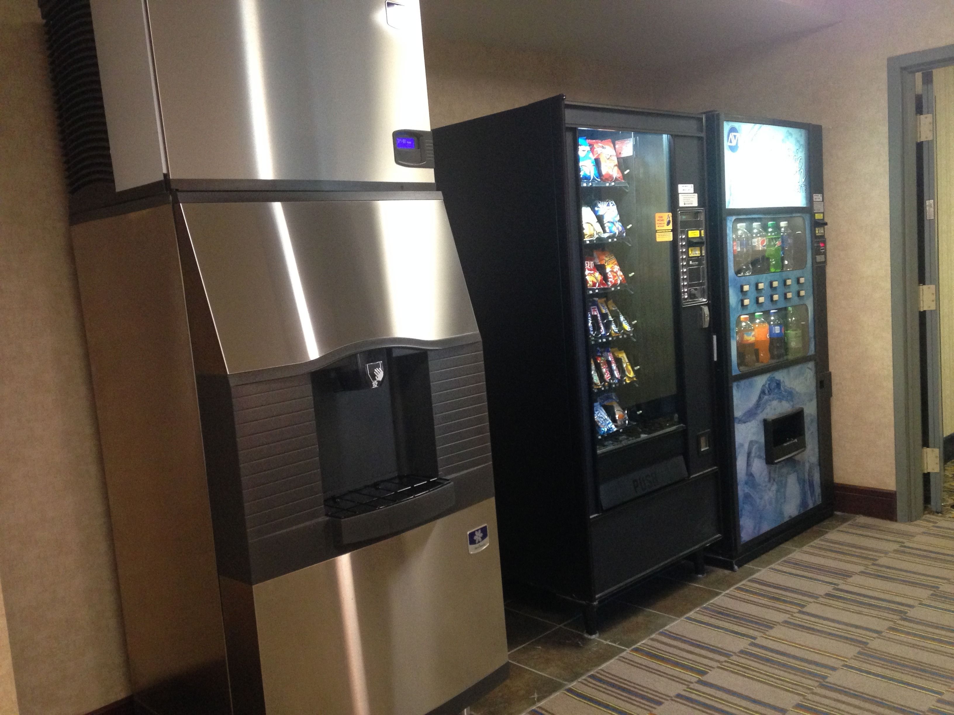 A vending machine and a water dispenser in a hallway.