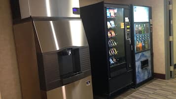 A vending machine and a water dispenser in a hallway.