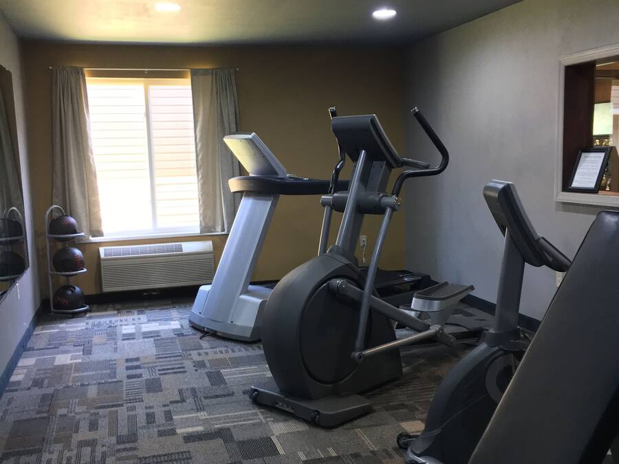 Un gimnasio con cintas de correr, bicicletas estáticas y un banco de pesas.