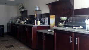 A hotel kitchen with granite countertops, stainless steel appliances, and wooden cabinets.