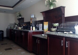 A hotel kitchen with granite countertops, stainless steel appliances, and wooden cabinets.