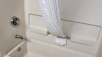 A bathtub with a white towel, a shower curtain, and a faucet.