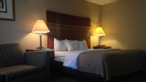 A hotel room with a bed, two bedside lamps, a chair, and a patterned carpet.