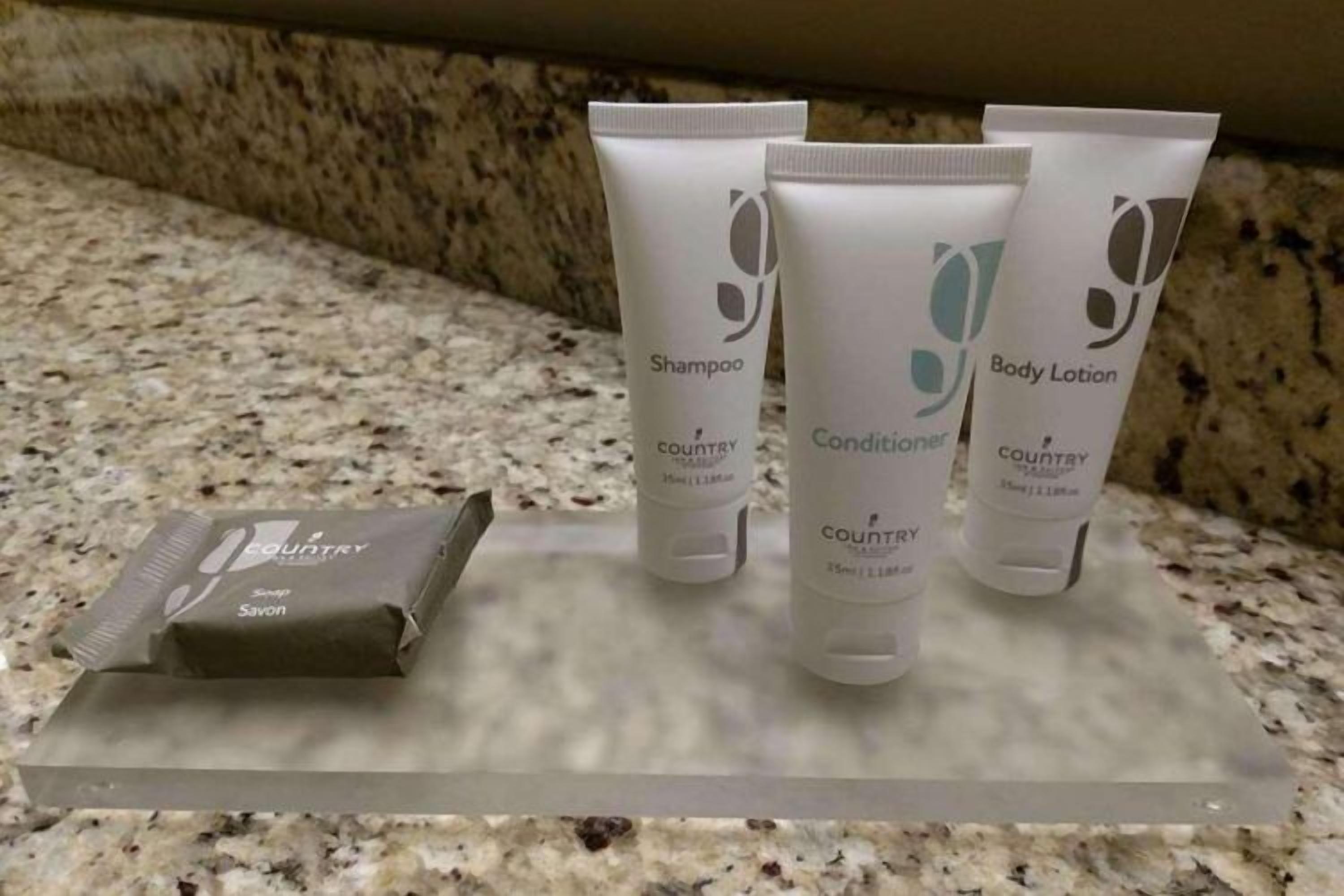 A countertop with three toiletry items: a shampoo, a conditioner, and a body lotion, all labeled 'COUNTRY.'